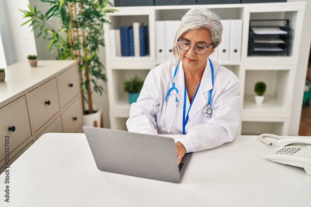 Middle age woman wearing doctor uniform working at clinic Middle age woman wearing doctor uniform working at clinic
