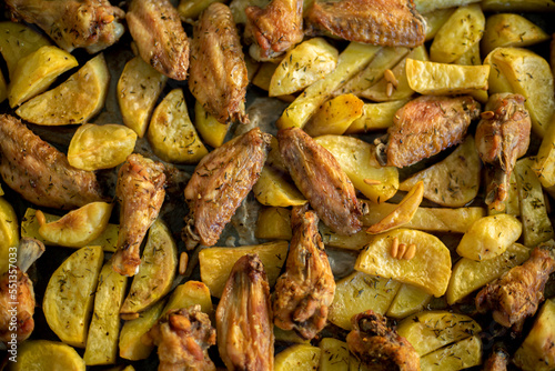 Traditional roast potatoes and chicken wings in the oven garnished with rosemary