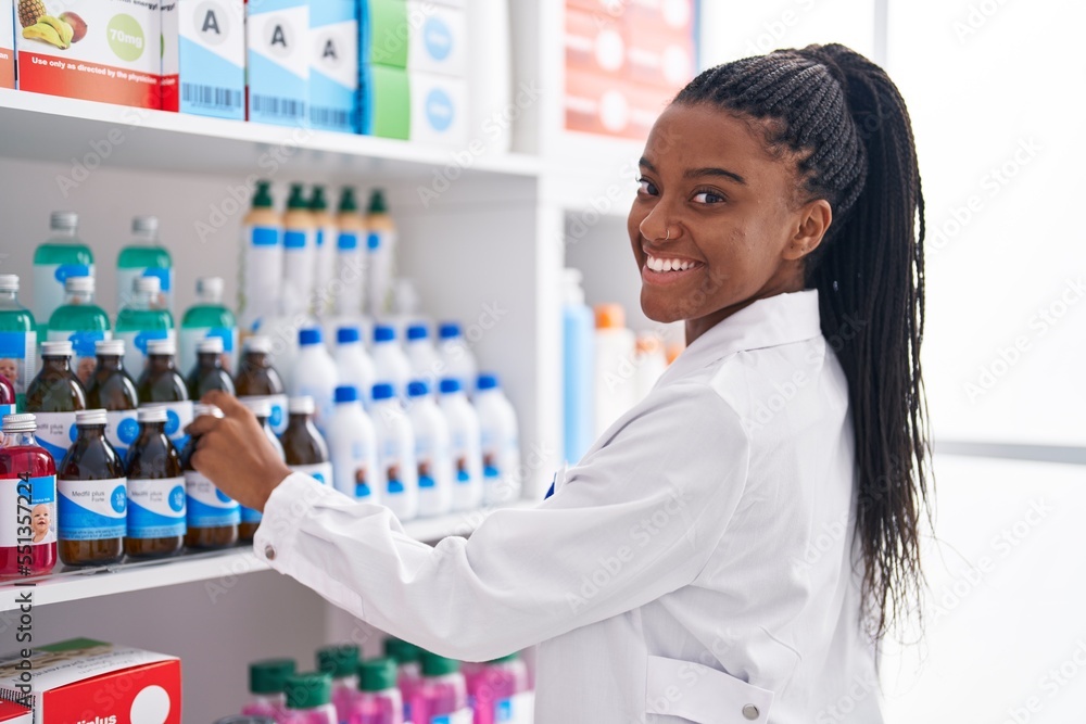 African american woman pharmacist smiling confident organize shelving at pharmacy