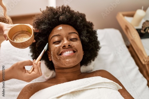 Young african american woman smiling confident having facial treatment at beauty center photo