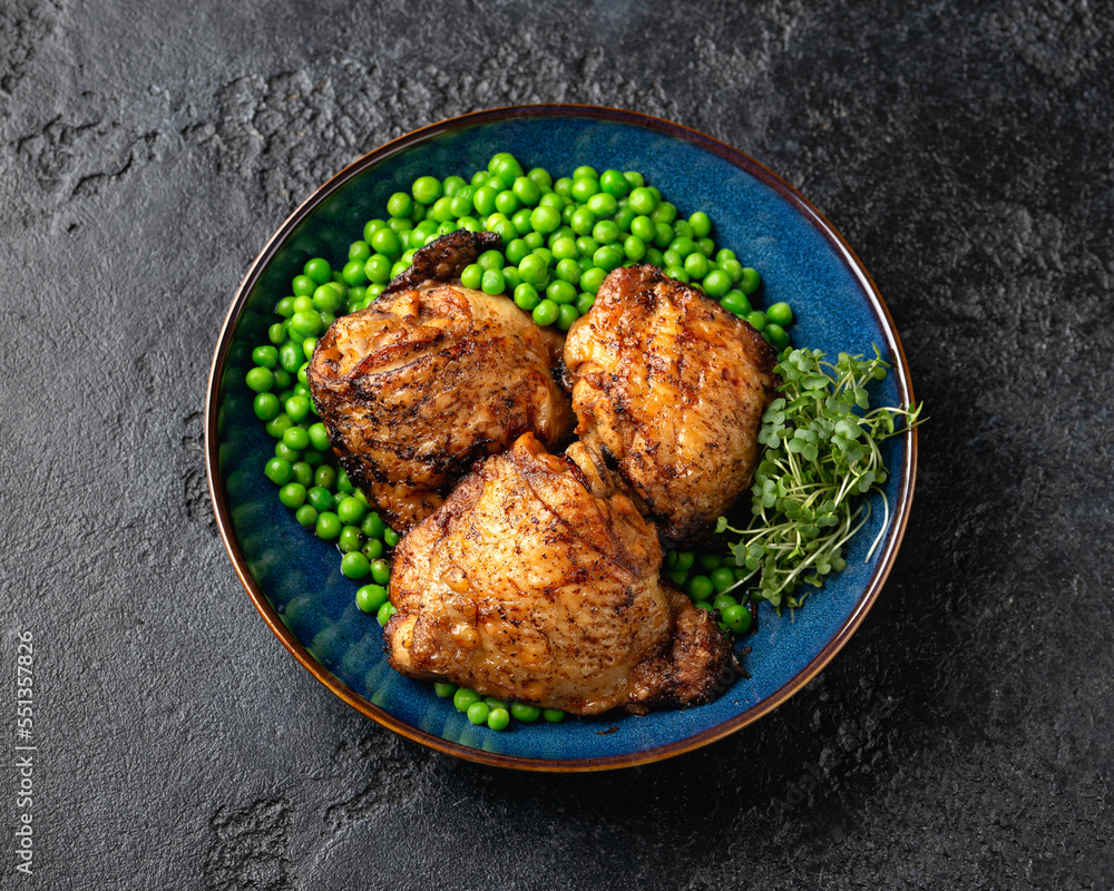 Baked Chicken thighs with green peas in blue plate Baked Chicken thighs with green peas in blue plate
