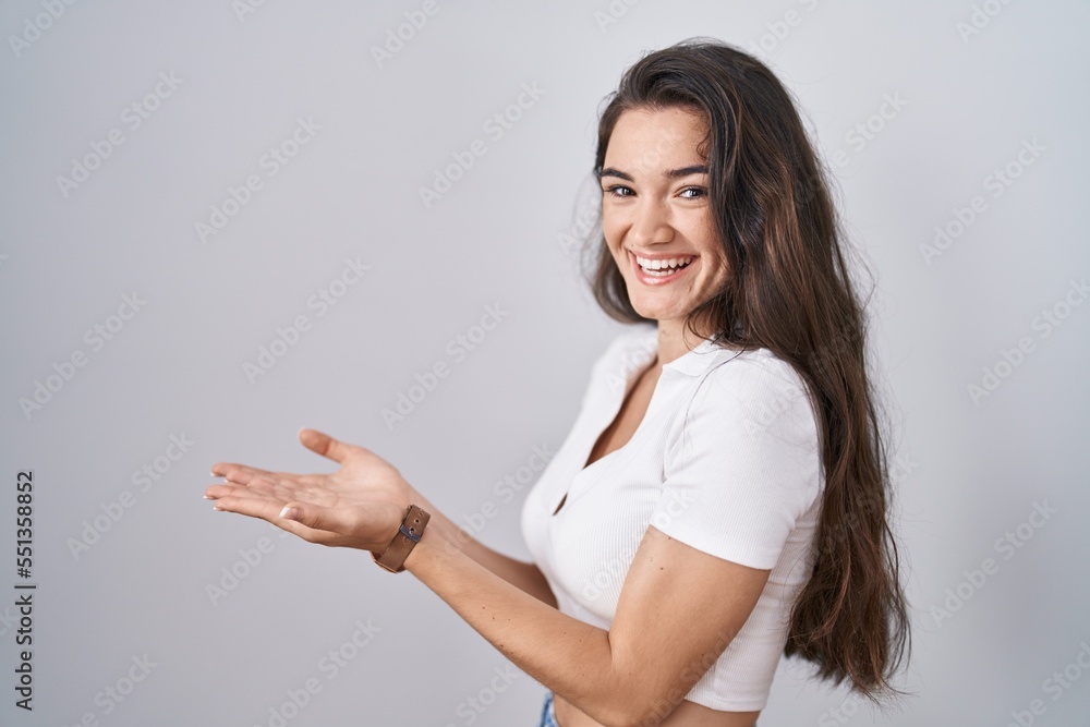 Young teenager girl standing over white background pointing aside with hands open palms showing copy space, presenting advertisement smiling excited happy Young teenager girl standing over white background pointing aside with hands open palms showing copy space, presenting advertisement smiling excited happy