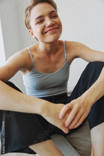 Teenage girl sitting on the couch at home smiling in home clothes and glasses with a short haircut, lifestyle without filters, free copy space