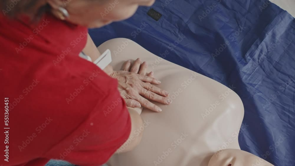 From above view of mature Caucasian woman practicing CPR heart massage on dummy on floor From above view of mature Caucasian woman practicing CPR heart massage on dummy on floor