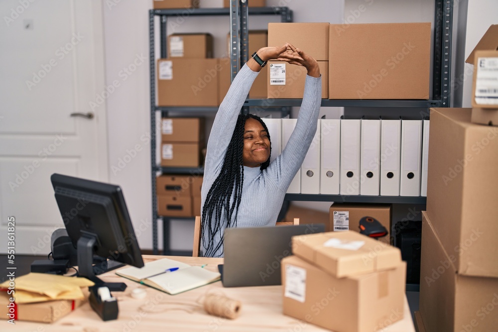African american woman ecommerce business worker using laptop stretching arms at street African american woman ecommerce business worker using laptop stretching arms at street