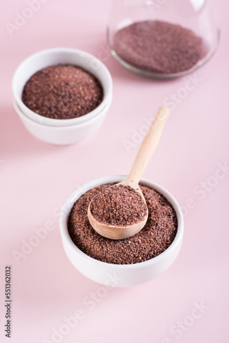 Black Himalayan kala namak salt in bowl with wooden spoon on pink background. Vertical view