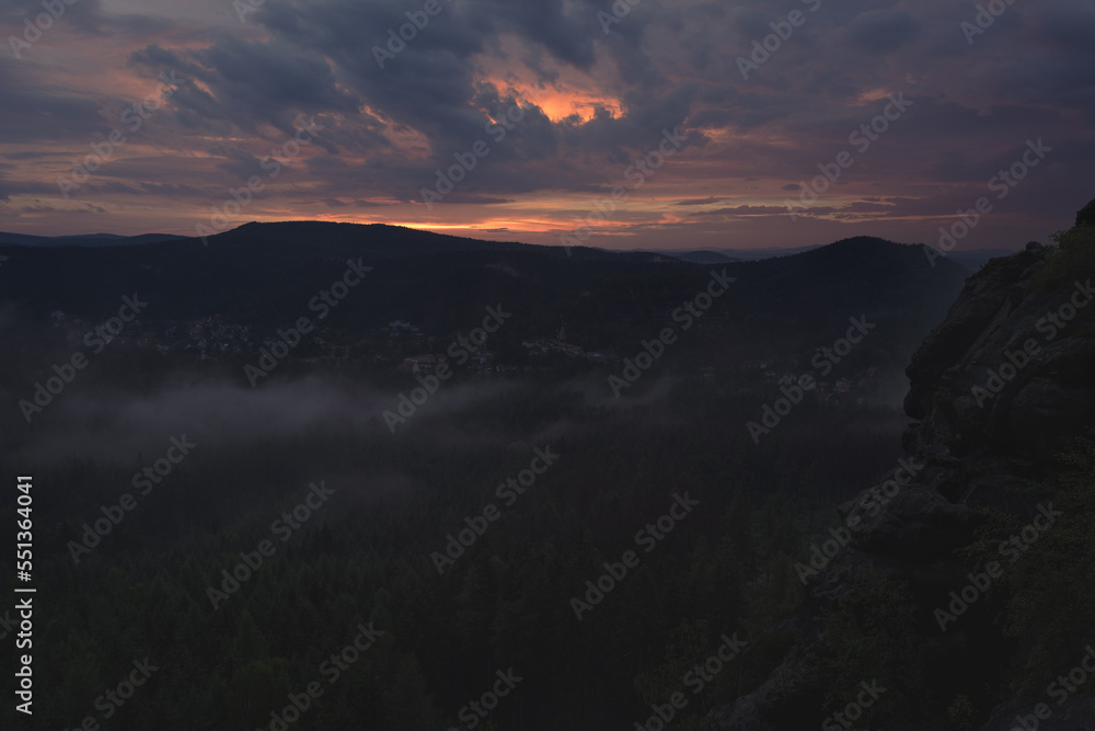 Zum Sonnenuntergang zieht Nebel durch das von Bergen umsäumte Tal. Nachtmittags regnete es. Das letzte Licht färbt die dunkeln Wolken. Mit Einbruch der Dunkelheit lösen sich die Nebelschwaden auf.