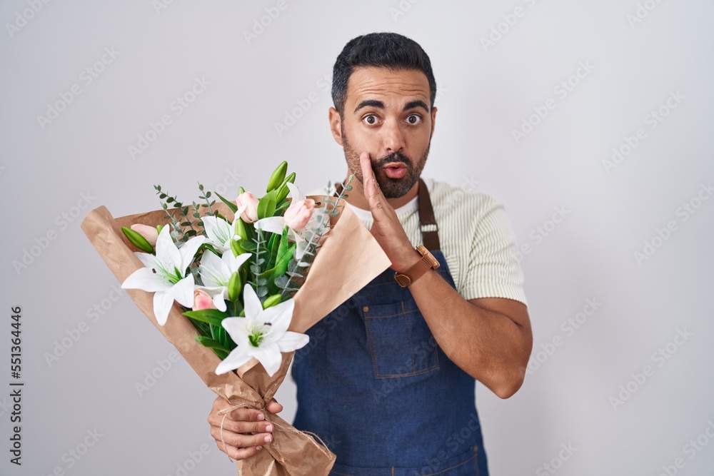 Hispanic man with beard working as florist hand on mouth telling secret rumor, whispering malicious talk conversation Hispanic man with beard working as florist hand on mouth telling secret rumor, whispering malicious talk conversation