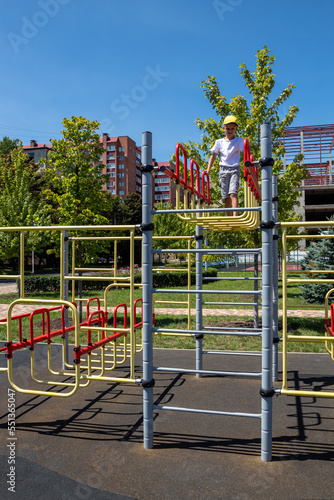 Boy moves on metal crossbars, plays on playground. Healthy summer activity for children. Free time to play. Children's favorite activity. Selective focus.