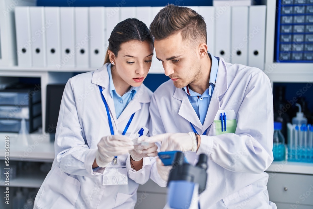 Man and woman scientists using smartphone looking sample at laboratory Man and woman scientists using smartphone looking sample at laboratory
