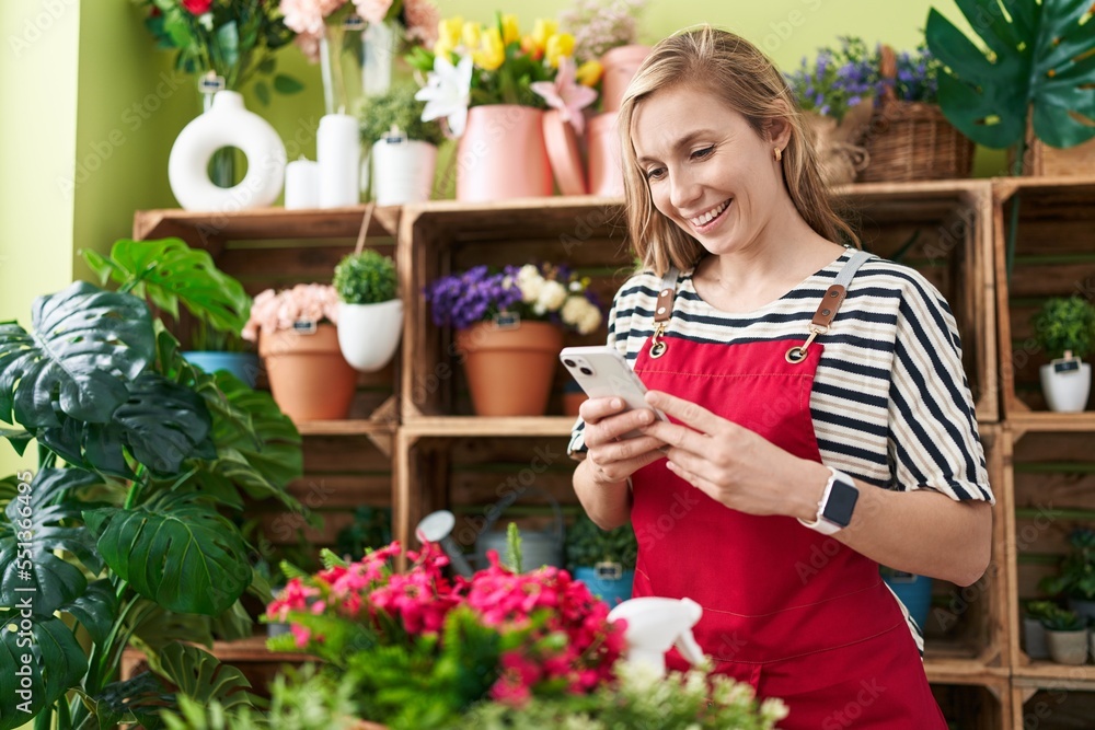Young blonde woman florist smiling confident using smartphone at flower shop