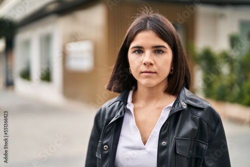 Young beautiful hispanic woman standing with serious expression at street