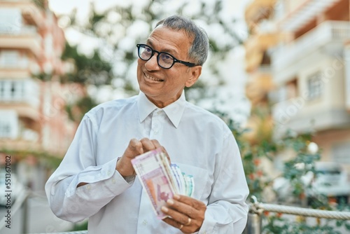 Middle age southeast asian man holding indian rupees banknotes at the city photo