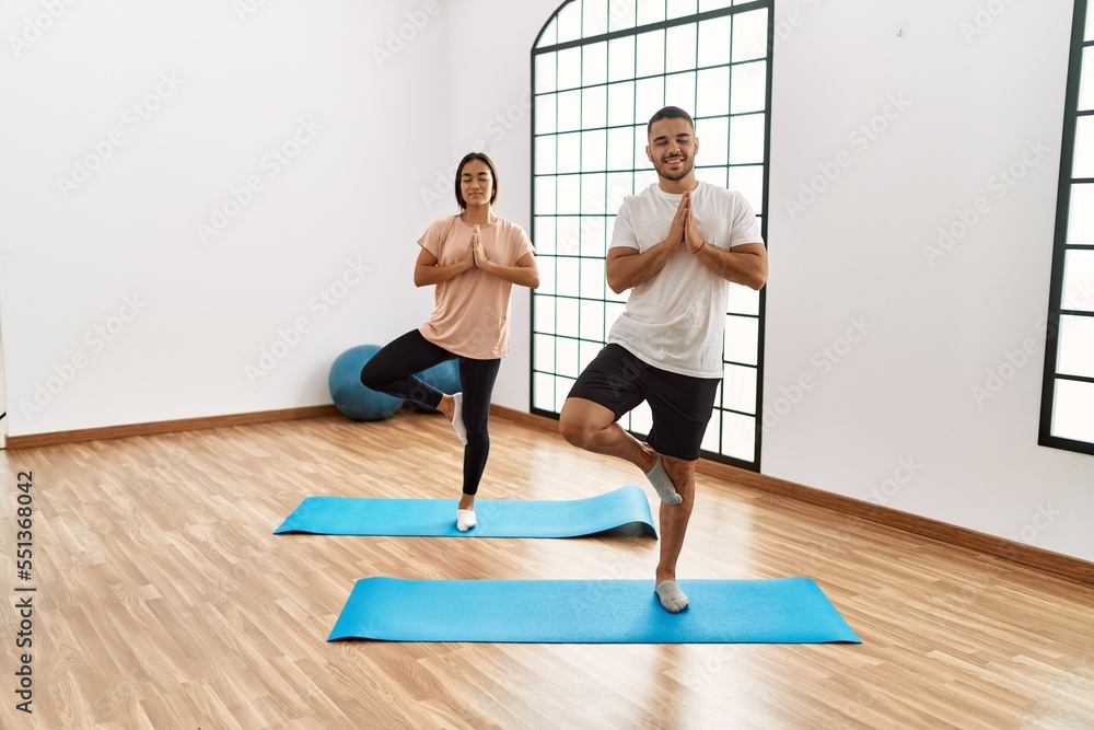 Latin man and woman couple smiling confident training yoga at sport center