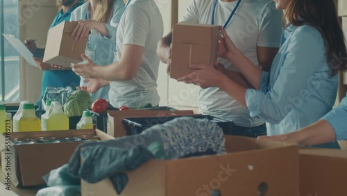 Charity, Donation, and Volunteering Concept - Group of Happy Smiling Volunteers Sorting Humanitarian Aid at Distribution or Refugee Assistance Center. Volunteer Warehouse