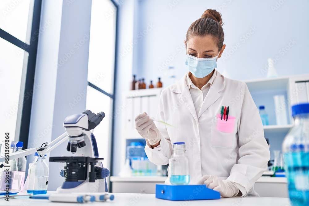 Young woman scientist weighing liquid at laboratory Young woman scientist weighing liquid at laboratory