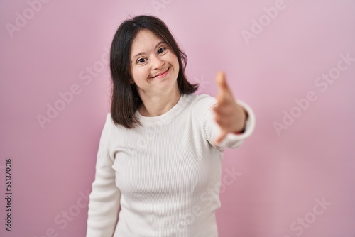 Wallpaper Mural Woman with down syndrome standing over pink background smiling friendly offering handshake as greeting and welcoming. successful business. Torontodigital.ca