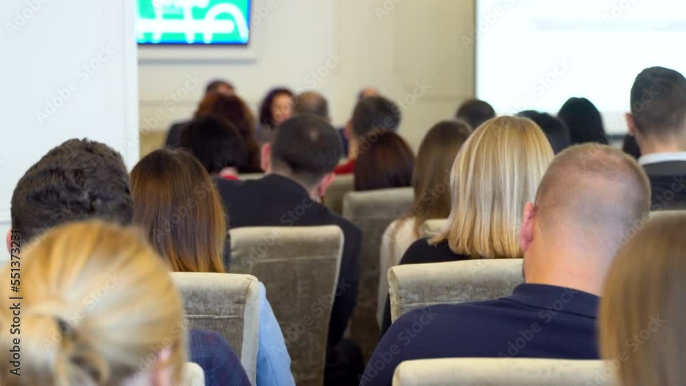 Speaker giving a talk in conference hall at business event. Business and Entrepreneurship concept. Focus on unrecognizable people in audience. Audience at the conference hall