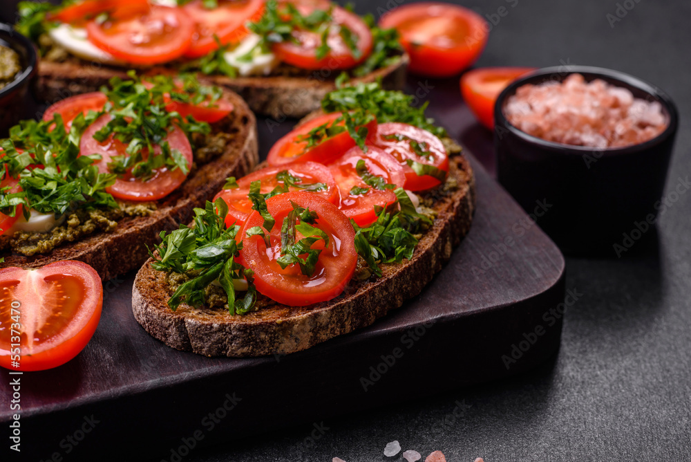 Tasty bruschetta with tomatoes, mozzarella, basil, spices and herbs