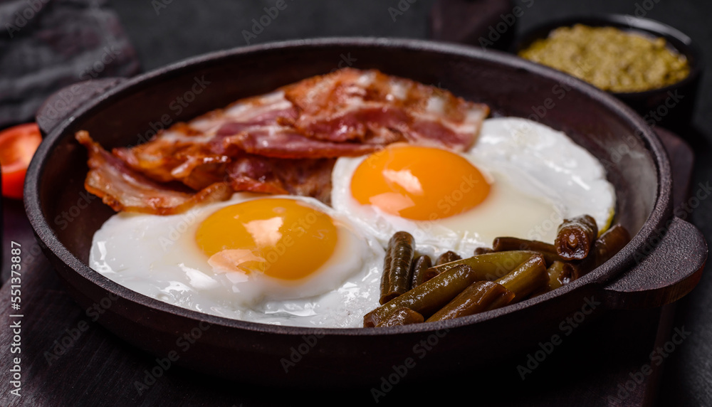 Tasty breakfast consists of eggs, bacon, beans, tomatoes, with spices and herbs Tasty breakfast consists of eggs, bacon, beans, tomatoes, with spices and herbs