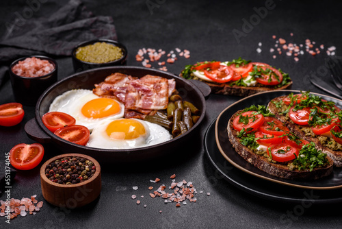 Tasty breakfast consists of eggs, bacon, beans, tomatoes, with spices and herbs