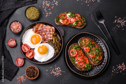 Tasty breakfast consists of eggs  bacon  beans  tomatoes  with spices and herbs