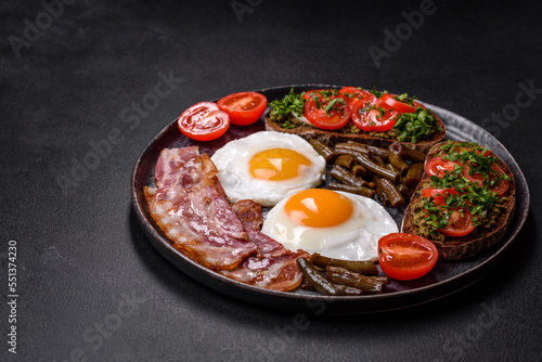 Tasty breakfast consists of eggs, bacon, beans, tomatoes, with spices and herbs