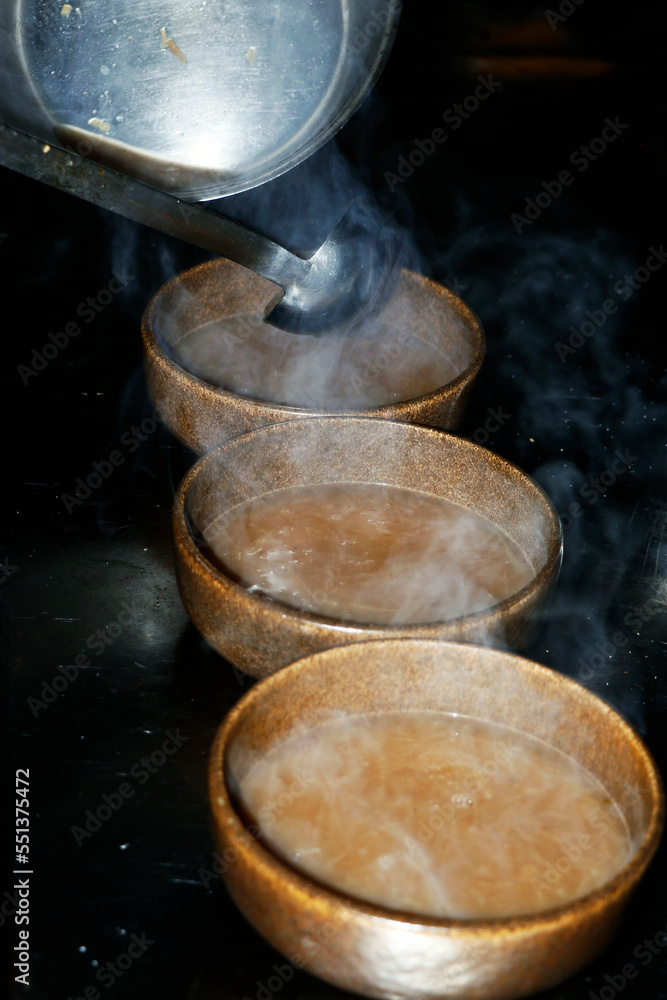 traditional brown onion soups pouring into a bowl