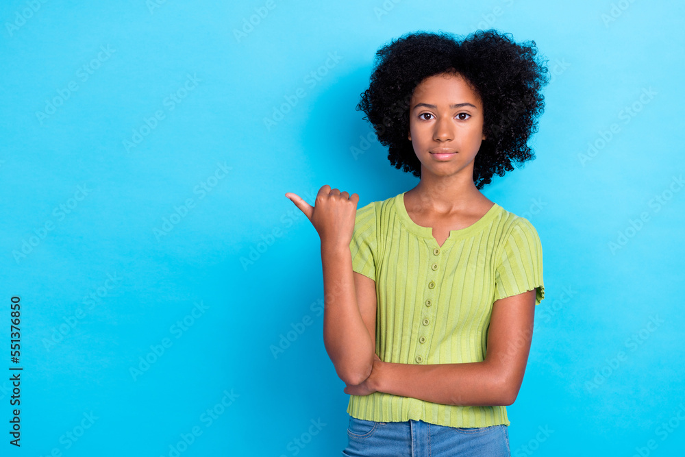 Photo of serious confident girl with perming hair dressed green t-shirt directing empty space sale isolated on blue color background Photo of serious confident girl with perming hair dressed green t-shirt directing empty space sale isolated on blue color background