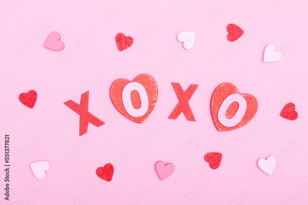 The inscription xo xo from wooden letters and hearts on a pink background. The concept of Valentine's day, love, dating and wedding. Kiss symbol. flat lay.