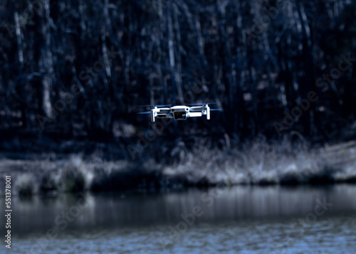 Drone hovering over lake with forest in background