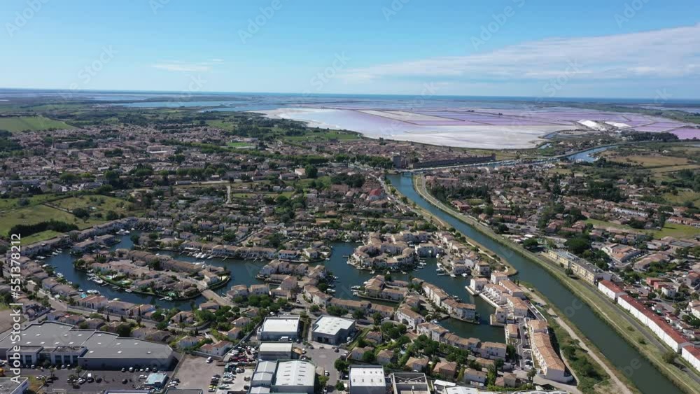 Beautiful residential marina in Aigues-Mortes along a canal with pink salt lakes in background aerial sunny day Beautiful residential marina in Aigues-Mortes along a canal with pink salt lakes in background aerial sunny day