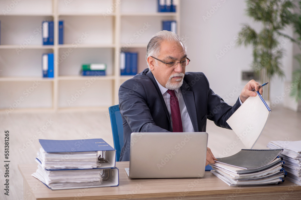 Old male employee sitting at workplace Old male employee sitting at workplace