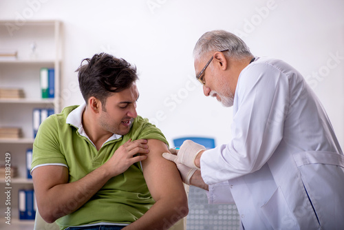 Young male patient visiting old male doctor in vaccination conce