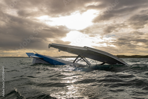 Float plane aka bush plane sinking in river water after a crash and flipping upside down in a storm under a cloudy sky photo