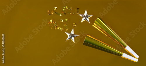 Фотография New Year celebration gold background with noisemakers, stars and confetti