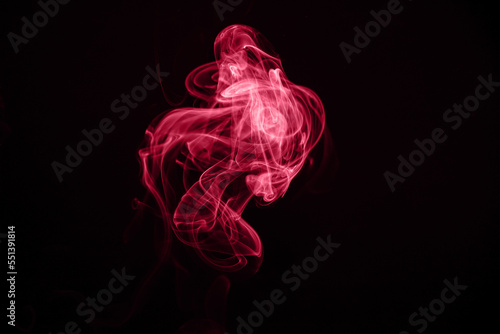 Unusual red smoke on a black background. Color of the year 2023 - Viva Magenta