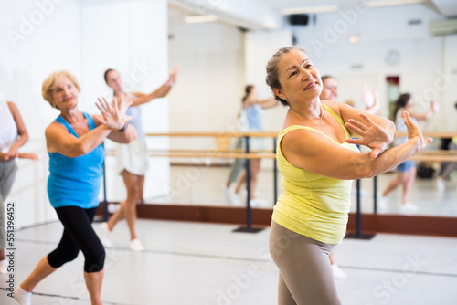 Portrait of a positive European woman enjoying energetic dancing at a group class in a modern dance studio
