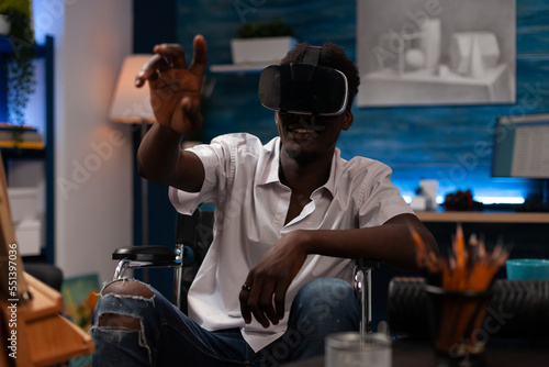 Modern artist with walking disease using virtual reality goggles to find inspiration within metaverse. African american sketcher navigating virtual reality to create professional artwork.