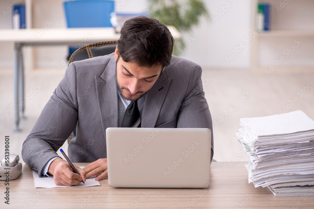 Young male employee and too much work in the office Young male employee and too much work in the office