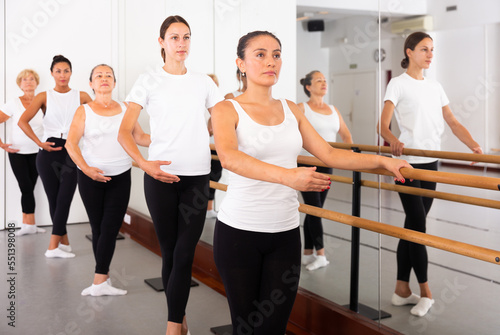 Latino woman rehearsing ballet dance in studio with other dancers