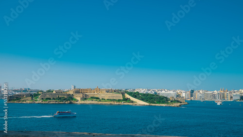 Ferry betweem Sliema and Valletta on malta visible sailing towards sliema in evening hours, cityscape of valletta in the background.