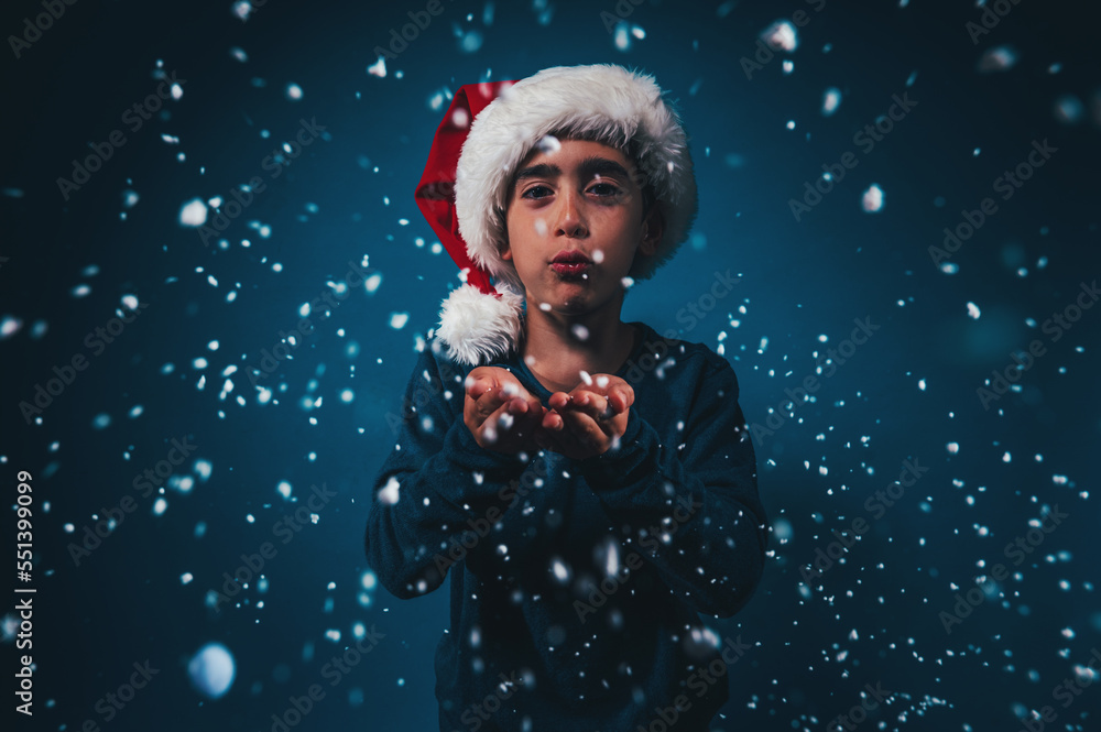 Child with Christmas hat blows to make the snow fly Child with Christmas hat blows to make the snow fly