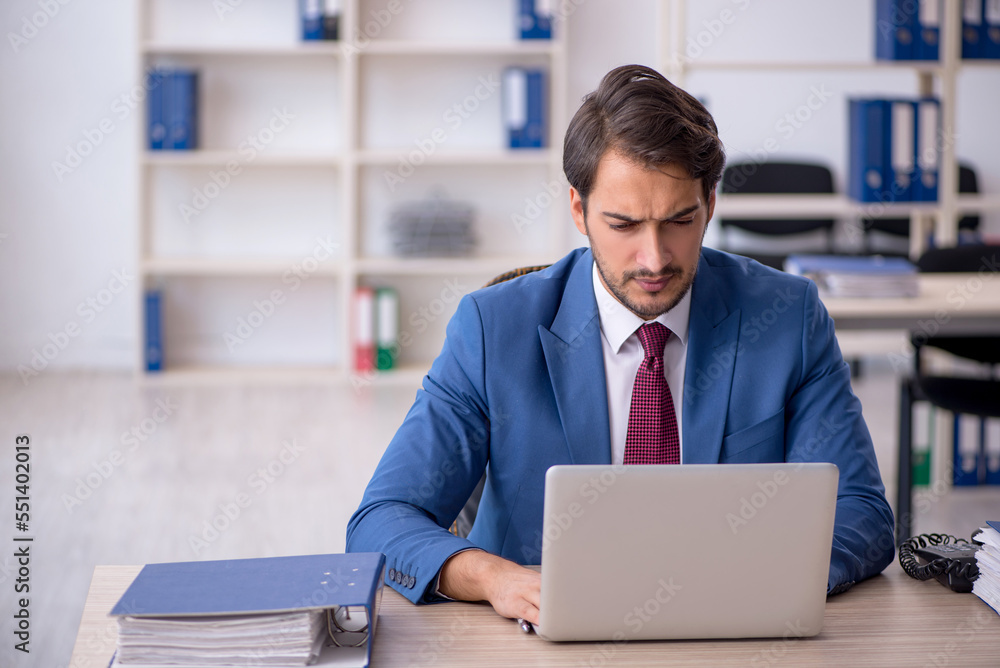 Young male employee and too much work in the office Young male employee and too much work in the office