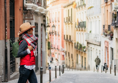 a tourist woman wearing a cap and backpack, walks through the streets of the historic center of Madrid. Walking tourism in spain. Concept of tourism and Spanish culture.