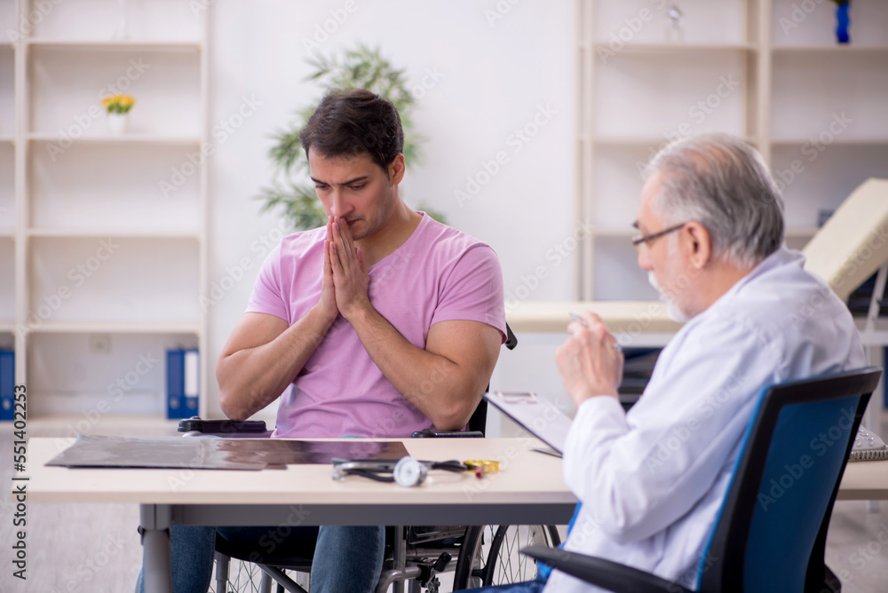 Fototapeta premium Young patient in wheelchair visiting old doctor