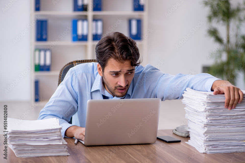 Young male employee and too much work in the office Young male employee and too much work in the office