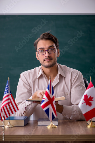 Young male teacher sitting in the classroom