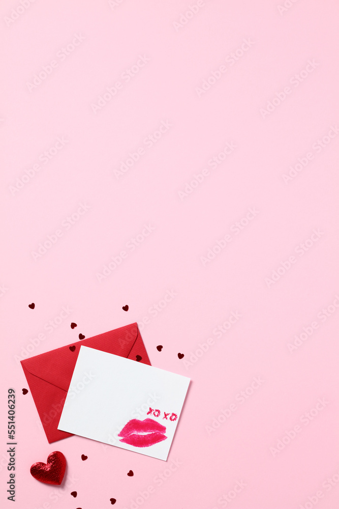 Romantic love letter concept. Blank paper card with lipstick kiss and red envelope on pastel pink background. Happy Valentines Day greeting card mockup.