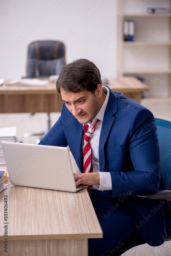 Young male employee and too much work in the office Young male employee and too much work in the office